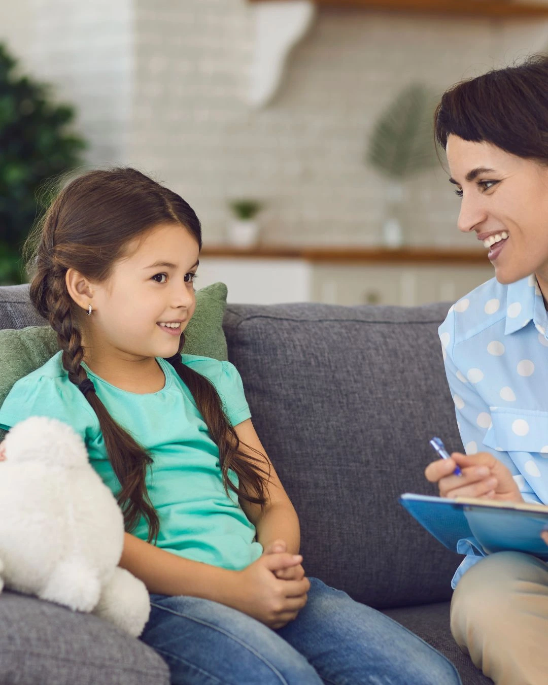 Young girl smiling during an in-home ABA therapy session in Albuquerque, NM, with a therapist offering supportive care.